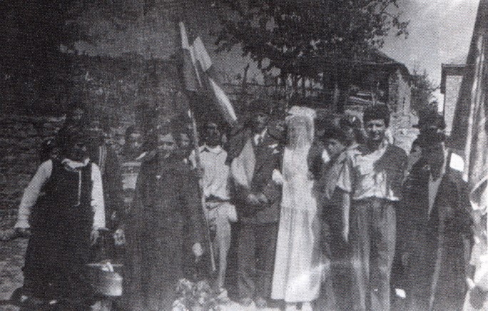 30. Πολυκάστανο Κοζάνης (μέσα 20ού αιώνα). Η πομπή του γάμου μετά το στεφάνωμα. Δίπλα στο γαμπρό και τη νύφη το μπαϊράκι. 30. Πολυκάστανο Κοζάνης (μέσα 20ού αιώνα). Η πομπή του γάμου μετά το στεφάνωμα. Δίπλα στο γαμπρό και τη νύφη το μπαϊράκι.